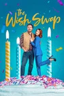 Two people stand on a giant birthday cake prop with lit candles; colorful background and The Wish Shop branding visible on the image.